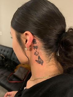 a woman with a tattoo on her neck and behind her ear is a black couch