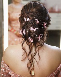 the back of a woman's head with flowers in her hair and pearls on it