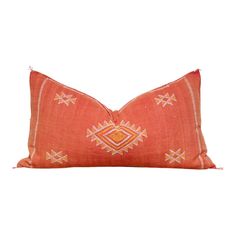 an orange and white pillow with geometric designs on the front, sitting on a white surface