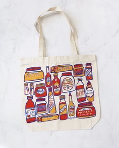 a tote bag with different types of condiments printed on it, sitting on a marble surface