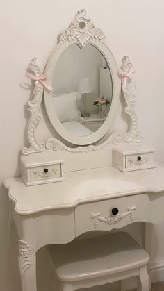 a white dressing table with a mirror and stool in front of the dresser is adorned with pink bows