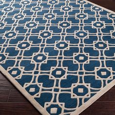 a blue and white rug with an intricate design on the bottom, in front of a wooden floor