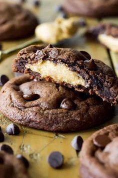 two chocolate chip cookies with one cookie in the middle and half eaten, on a yellow surface