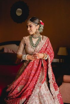 a woman in a red and white bridal outfit is standing with her hands on her hips