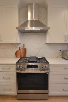 a stove top oven sitting inside of a kitchen next to white cupboards and drawers