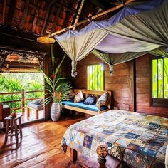 a bed sitting inside of a bedroom on top of a wooden floor next to a window