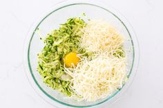 a glass bowl filled with shredded cheese and an egg sitting on top of other ingredients