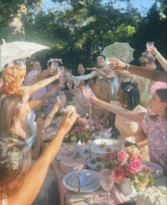 a group of people standing around a table with plates and cups in front of them