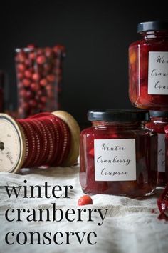 jars filled with cranberry preserves sitting on top of a table next to candy