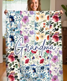 a woman is holding up a quilt with the word grandma written in florals on it