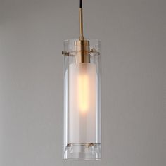 a glass and brass light hanging from a ceiling fixture with a white wall in the background