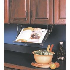 an open book is sitting on the counter next to a bowl of food and utensils