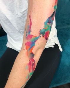 a woman's arm with colorful paint splattered on it