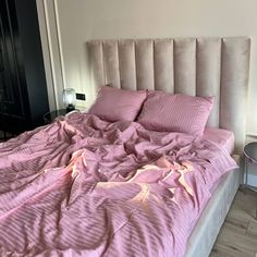 an unmade bed with pink sheets and pillows