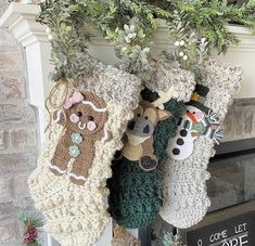 three christmas stockings hanging from a mantel decorated with crocheted animals and snowmen