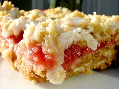 a piece of cake with icing and strawberries on it sitting on a plate