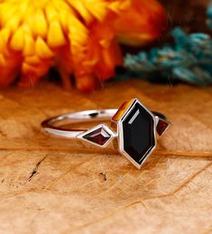 a close up of a ring on a wooden surface with flowers in the back ground