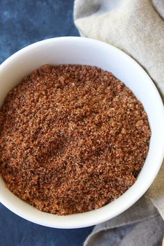 a white bowl filled with spices sitting on top of a blue table cloth next to a napkin