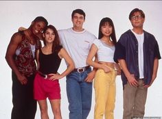 a group of young people standing next to each other in front of a white wall