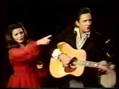 a man and woman standing next to each other while holding guitars in front of them