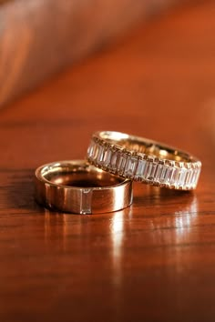 two wedding rings sitting on top of a wooden table