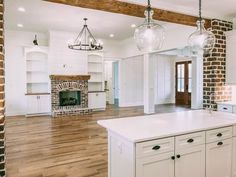 an empty kitchen with white cabinets and brick fireplace