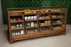 a display case filled with lots of different types of items in front of a green tiled wall