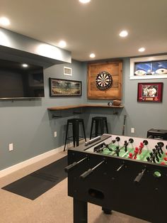 a game room with foosball, bar stools and darts on the wall