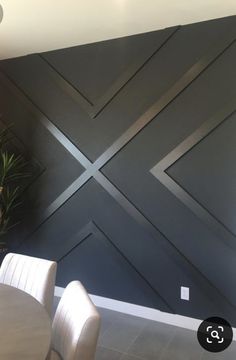 a dining room table and chairs in front of a wall with an x pattern painted on it