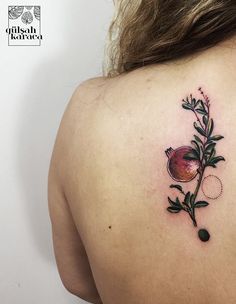 a woman's back with a flower tattoo on her left shoulder and an olive branch in the middle