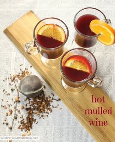 three glasses of hot mulled wine on a cutting board with orange slices and spices