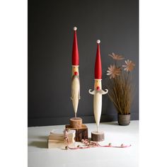 two wooden candlesticks with red and white hats on them sitting next to each other