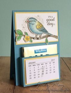 a desk calendar sitting on top of a wooden table next to a blue and white wall