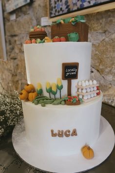 a three tiered white cake with lots of decorations on it's side and a sign that says luga