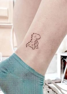 a small tattoo on the ankle of a woman's leg that has a dog in it