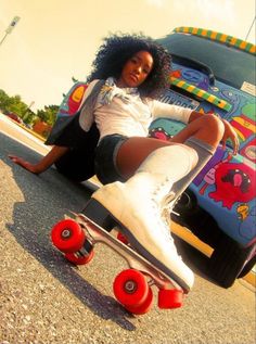 a woman sitting on top of a skateboard in front of a vehicle with wheels