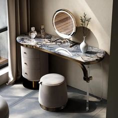 a vanity with a mirror, stool and vase on the table in front of it