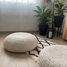 two crocheted poufles sitting on the floor in front of a window