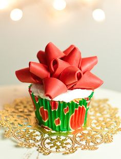 a cupcake decorated with red bows on top of a doily