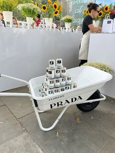 a white wheelbarrow filled with cans of prada