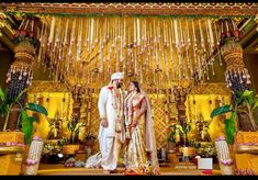 a man and woman standing in front of a stage with flowers hanging from the ceiling