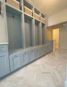 an empty room with gray cabinets and white tile flooring on the walls, along with herringbone tiles