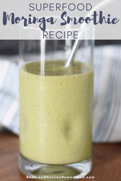 a glass filled with green smoothie sitting on top of a wooden table