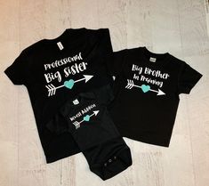 "Set of 3 personalized matching sibling shirts! (wording can be changed, big, middle, sister etc..) Shown in black shirts with aqua accents (names can be added under the arrow to match the heart) This set shown says Professional big sister, big brother in training, newest addition. Add one shirt at a time to your cart and purchase all together to make your perfect set! These are adorable to welcome a new baby into the family! Makes a sweet personalized gift for a mom with her 3rd child! They als Black T-shirt With Name Print For Parenting, Fitted Family Matching T-shirt With Name Print, Family Matching Fitted T-shirt With Name Print, Fitted T-shirt For Family Matching Gift, Father's Day Personalized Matching T-shirt, Black Custom Print Top For Gender Reveal, Black Family Matching T-shirt For Gender Reveal, Customizable Matching T-shirt For Family, Customizable Matching Family T-shirt