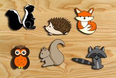 several different types of animals on a wooden surface, including an owl, hedgehog, fox, and raccoon