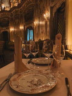 a table set for two with wine glasses and napkins on it in a fancy setting