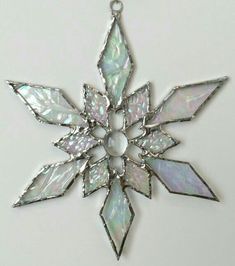 a white snowflake ornament hanging from a chain on a white surface