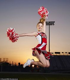 a cheerleader jumping in the air with her pom - poms at sunset