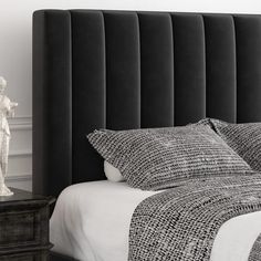 a black and white photo of a bed with a statue on the nightstand next to it