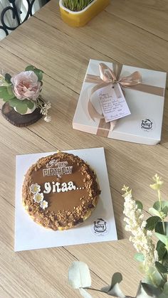 a birthday cake sitting on top of a wooden table next to flowers and greeting cards